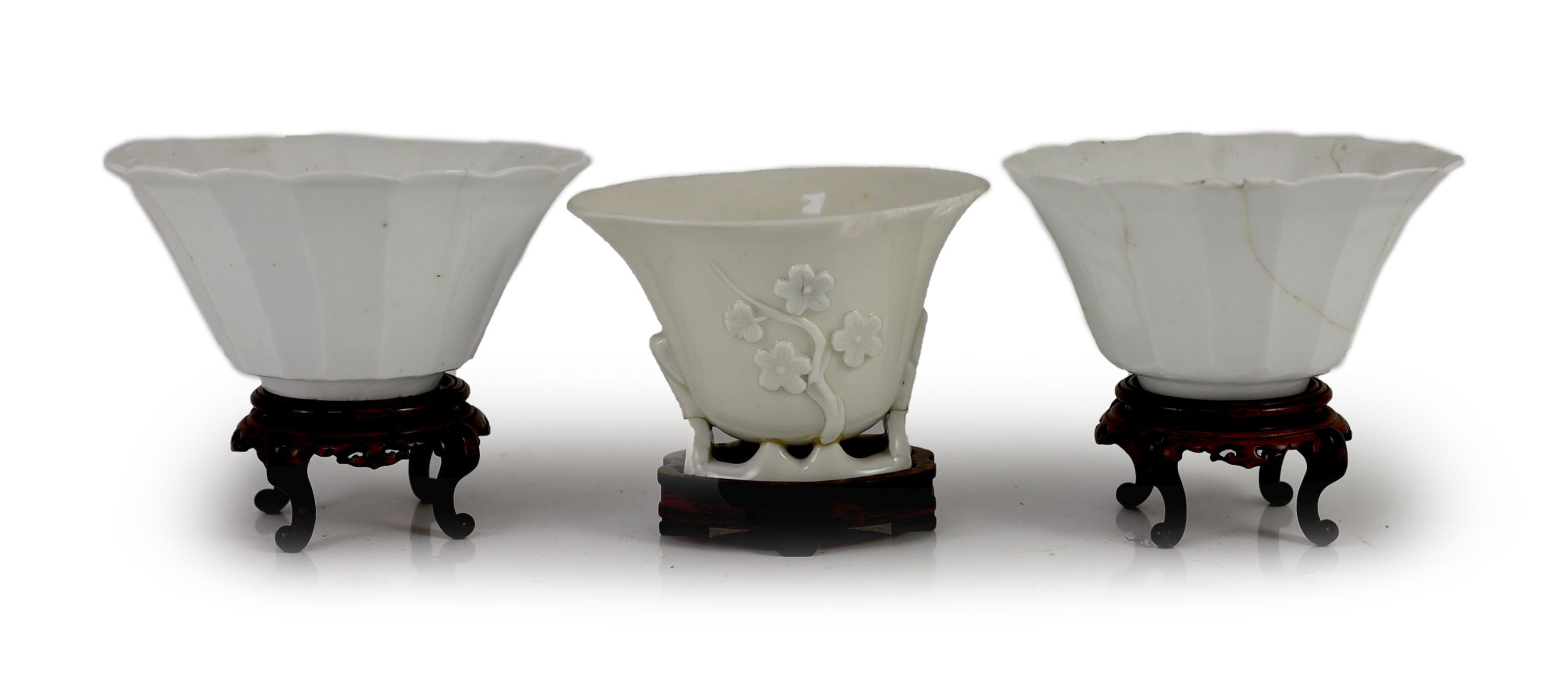 A pair of Chinese blanc-de-chine fluted bowls and a similar libation cup, Dehua kilns, 17th century, 6.5cm high & 7.5cm wood stands, damage